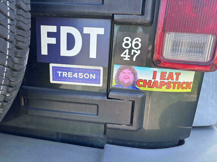 Bumper stickers on a vehicle featuring humorous and unhinged messages including I eat chapstick and TRE45ON.