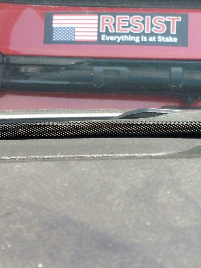Bumper sticker on a red vehicle with an American flag and the word RESIST, reading everything is at stake.