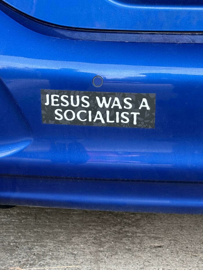 Blue car bumper with a hilarious and unhinged bumper sticker stating Jesus was a socialist.