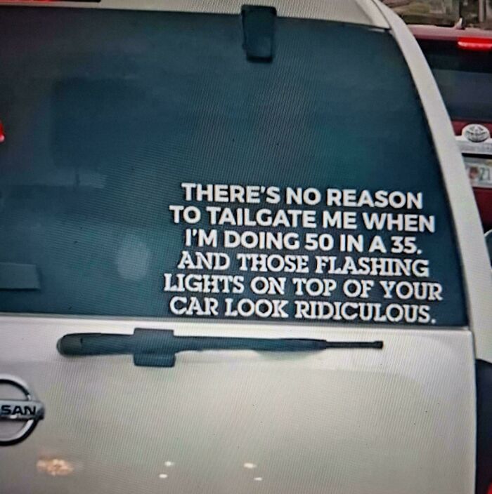 Funny and unhinged bumper sticker about speed and flashing lights on a white Nissan vehicle’s rear window.