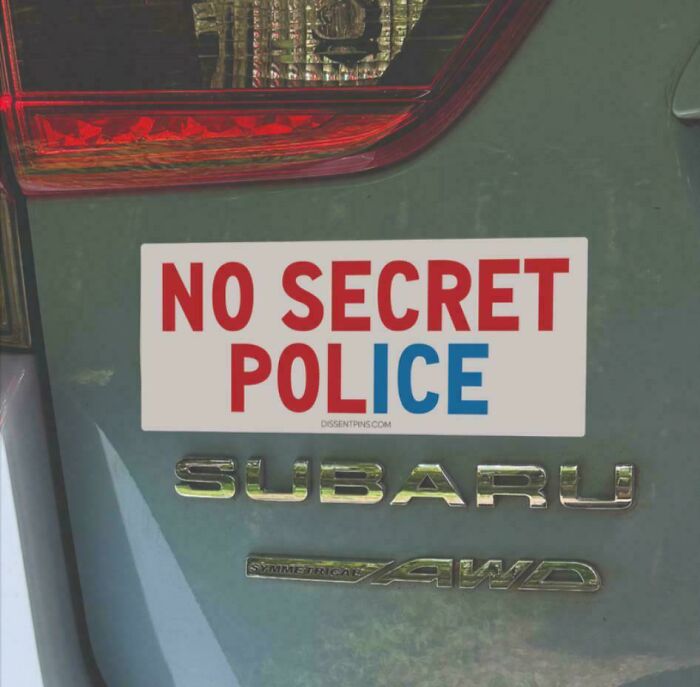 Funny and unhinged bumper sticker on a Subaru car saying no secret police in red and blue letters.