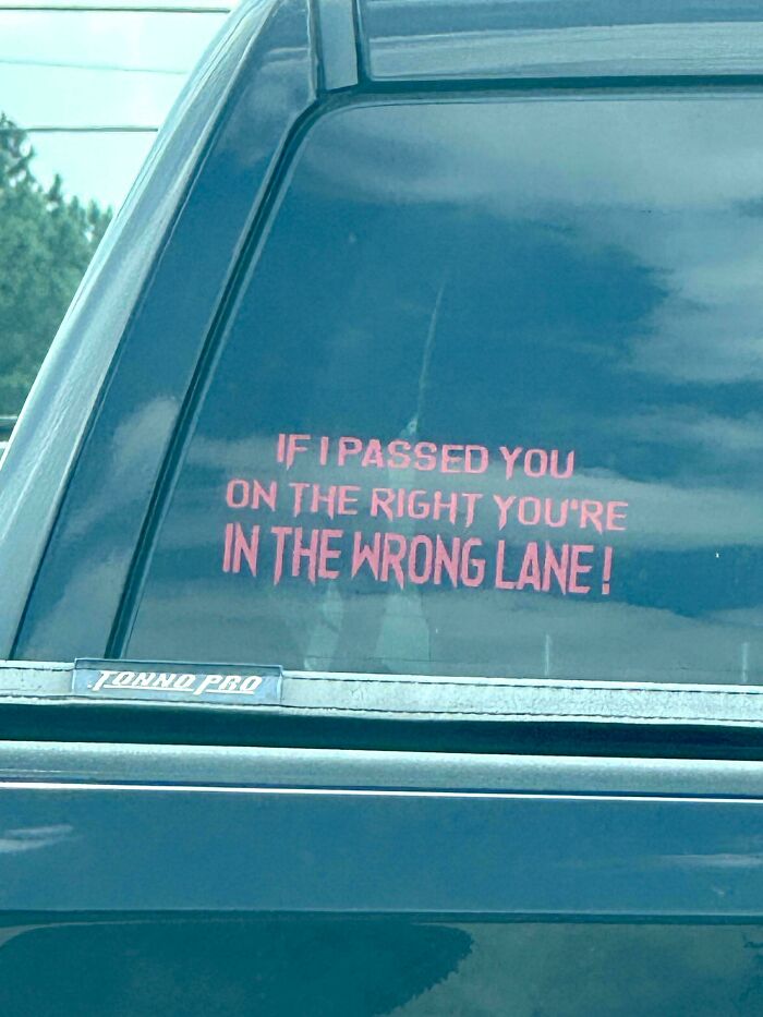 Funny and unhinged bumper sticker in red text on a dark vehicle window about passing on the right lane mistake.