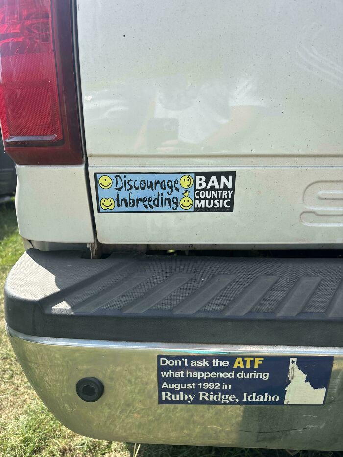 Humorous and unhinged bumper stickers on a truck, including one that says ban country music and discourage inbreeding.