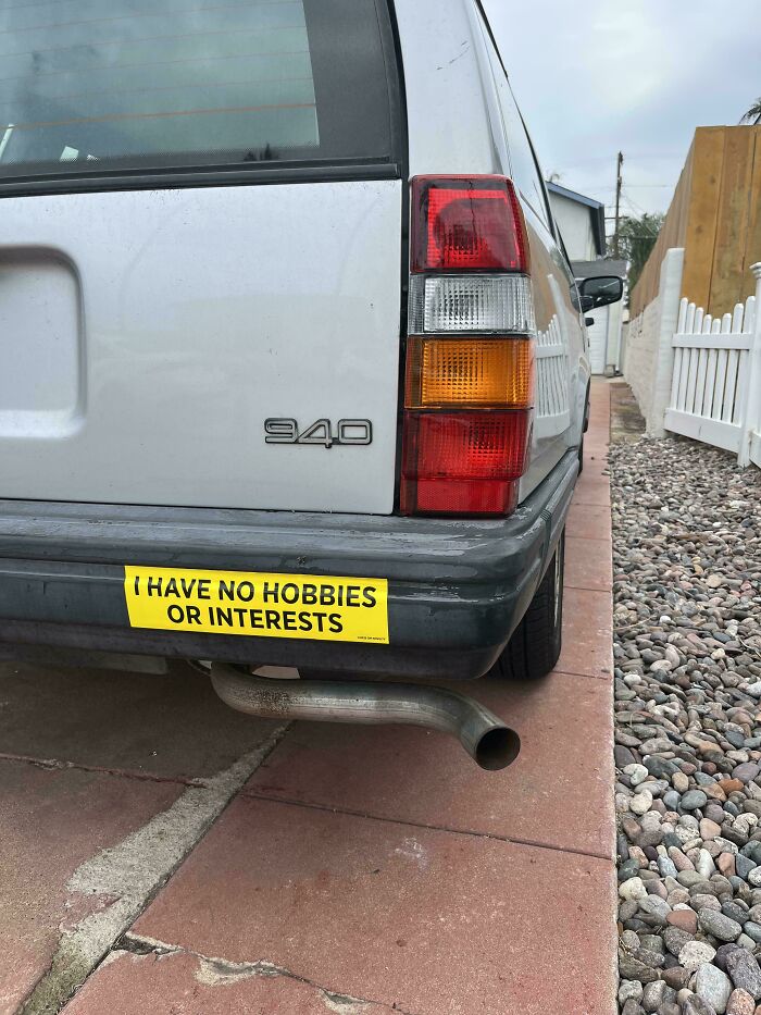 Back of a gray 940 car with a hilarious bumper sticker saying I have no hobbies or interests.