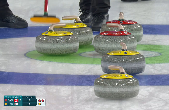 Curling stones arranged in a way that creates a misleading and confusing photo that seems like a glitch in real life.
