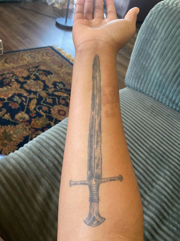 Tattoo of a sword on a forearm, showing a simple design that fits the truly awful tattoos category.