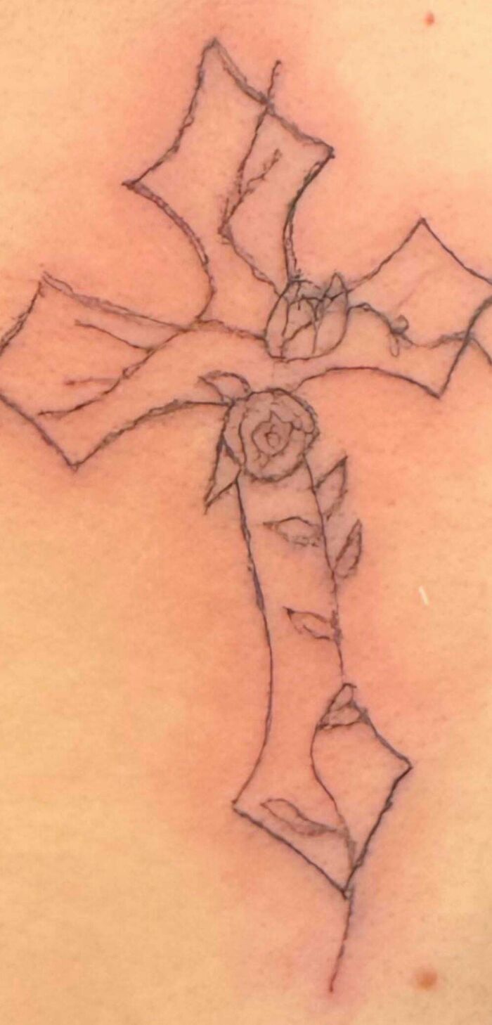 Poorly drawn cross tattoo with rough lines and unclear details, an example of truly awful tattoos that are funny and tragic.