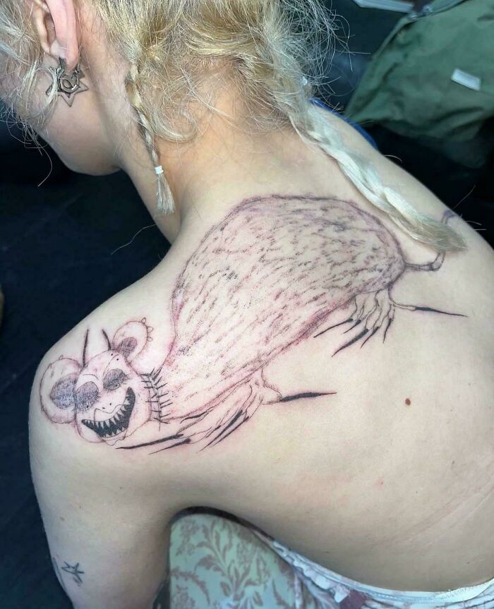 Person with a large, poorly executed tattoo of a bizarre creature on their upper back, showcasing awful tattoos.
