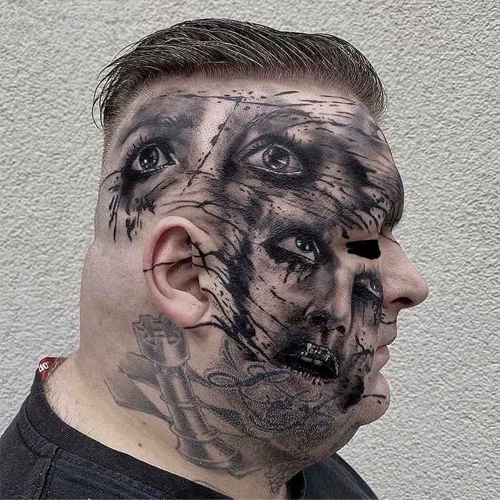 A close-up side view of a man with a truly awful tattoo covering his entire face depicting multiple distorted eyes and faces.