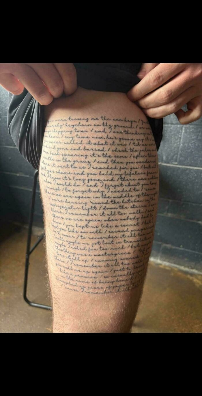 Tattoo of dense handwritten text covering a person's thigh, showcasing one of the truly awful tattoos that are permanent.