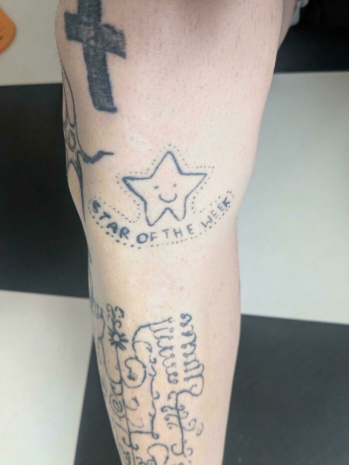 Close-up of funny and truly awful star tattoo on leg with text star of the week among other permanent tattoos.