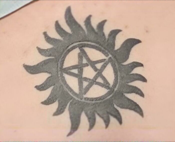 Black sun and star tattoo on skin showing one of the truly awful tattoos that are funny and permanent.