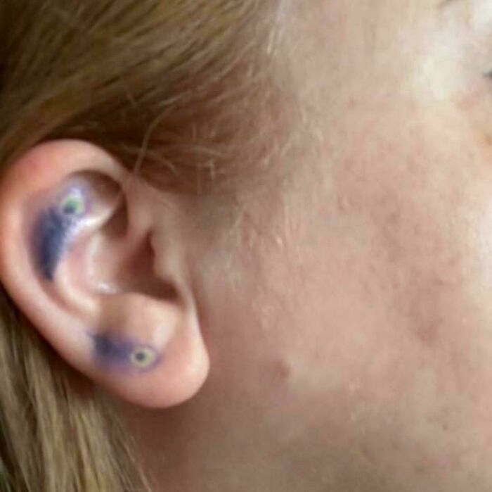 Close-up of a person's ear with truly awful tattoos that appear funny and tragic, highlighting permanent ink mistakes.