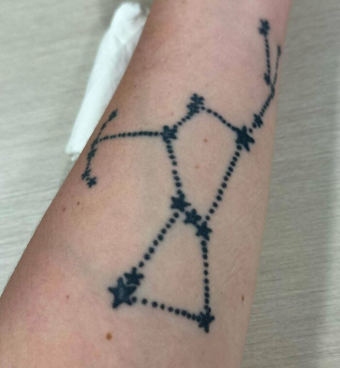 Black dot and star constellation tattoo on forearm showing a truly awful tattoo with uneven lines and spacing.