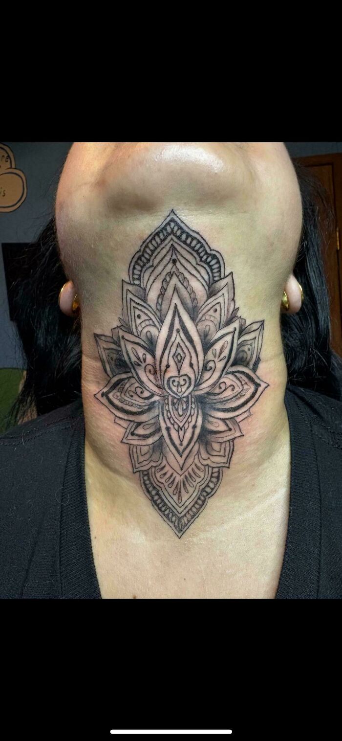 Black and gray neck tattoo of an intricate floral pattern showing detailed linework and shading in a symmetrical design.