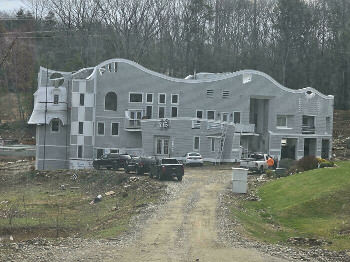 A large, oddly shaped gray mansion under construction, inspired by mansions but built as a Temu version.