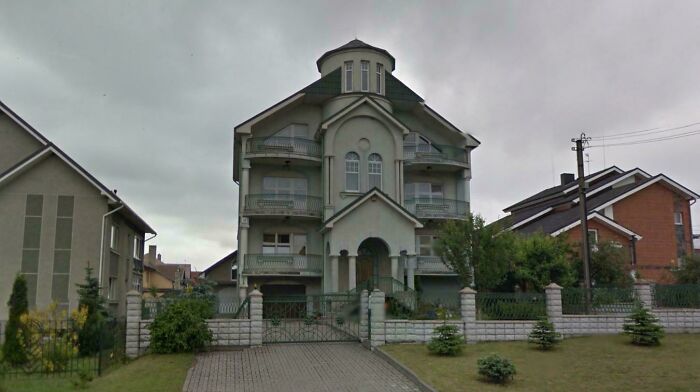 A multi-story gray house with balconies and a turret, reflecting a Temu-inspired mansion design.