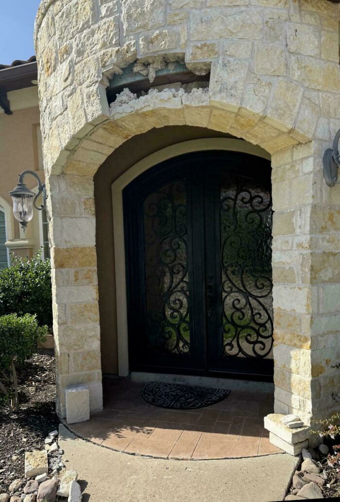 A close-up of a damaged stone archway at the entrance of a mansion-inspired home, like a Temu version.
