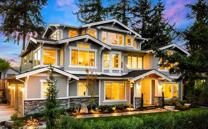 A beautiful, sprawling mansion with elegant landscaping and warm interior lighting.