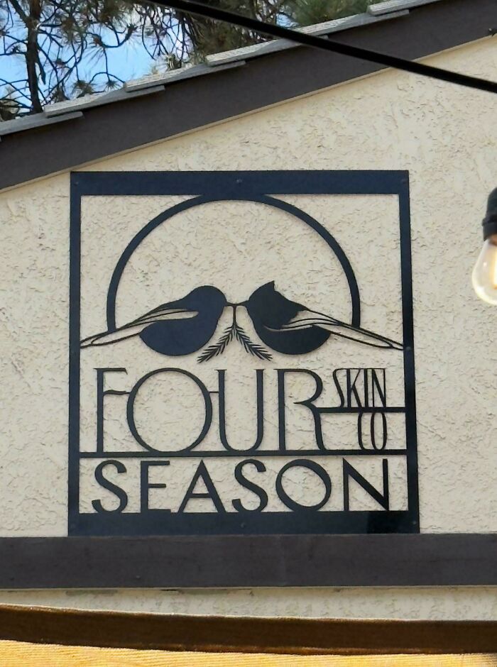 A hilariously confusing poor sign design, showing a metal cutout sign on a building that reads FOURSKIN CO SEASON.