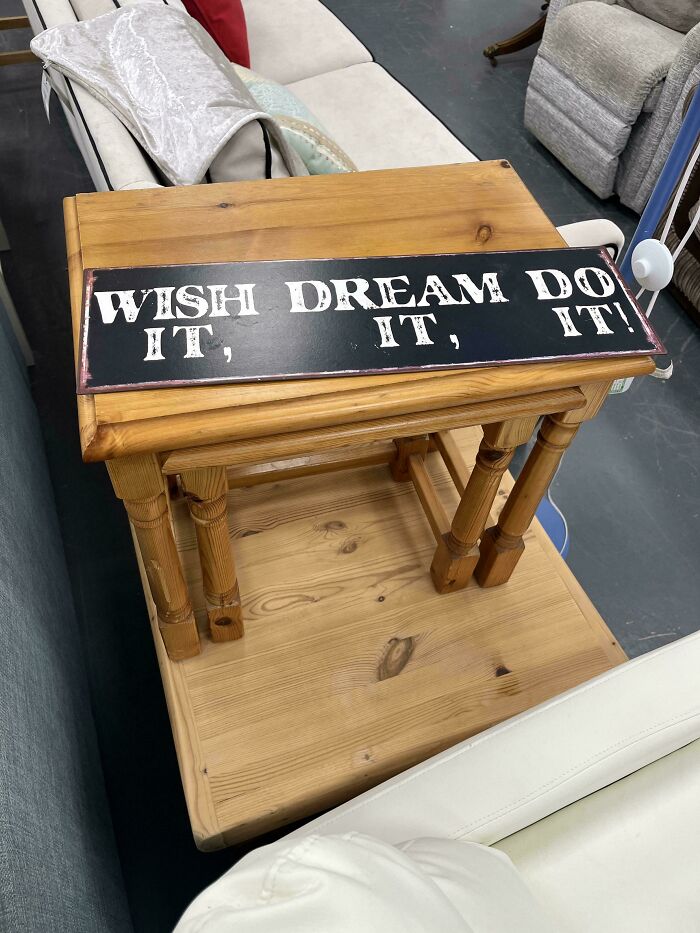 A sign with poor design on a wooden table displays a confusingly split message: Wish Dream Do It.