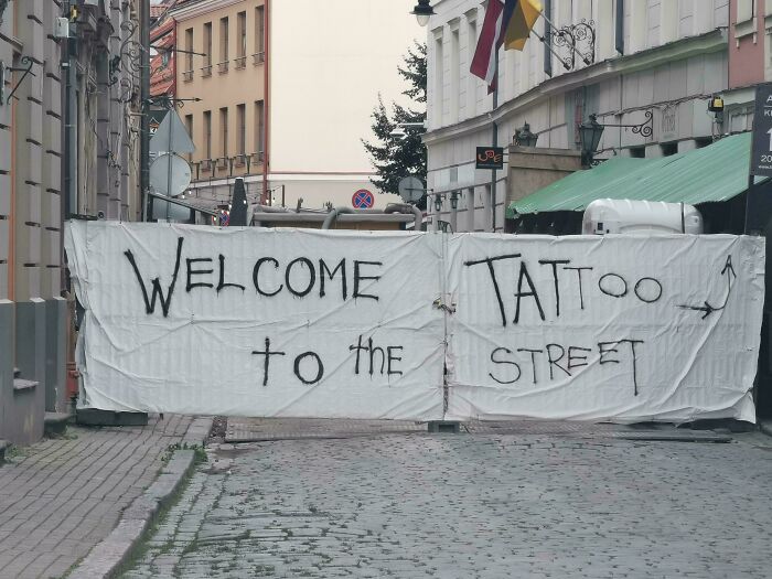 A hilariously confusing message on a sign banner that reads 'WELCOME to the TATTOO STREET'