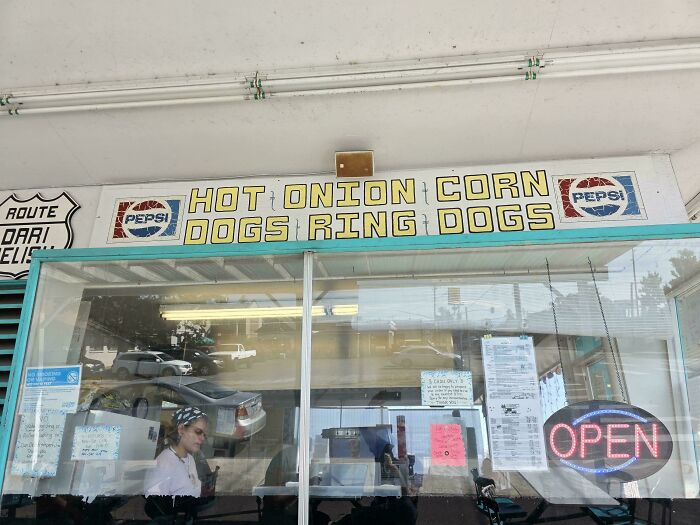 A roadside food stand with a confusing message on its sign, HOT ONION CORN DOGS RING DOGS, due to poor sign design.