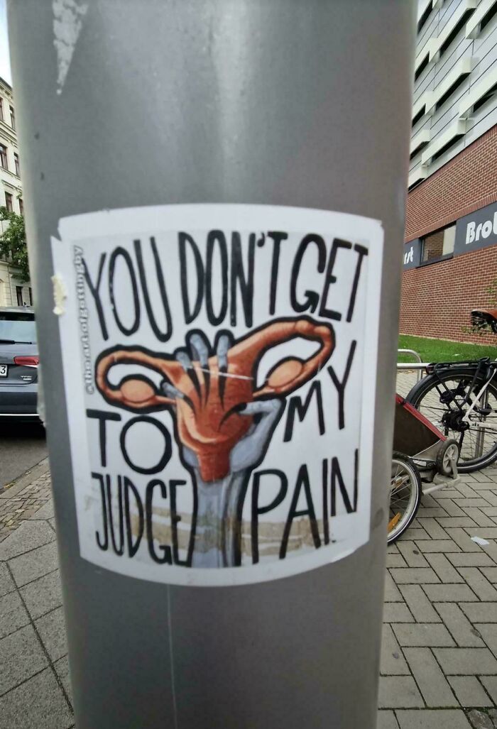 A sticker on a pole with a confusing message, YOU DON'T GET TO JUDGE MY PAIN, showcasing poor sign design.
