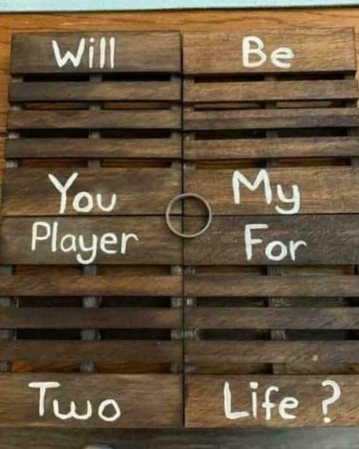 A wooden pallet sign with a hilariously confusing message asking WILL BE YOU MY PLAYER FOR TWO LIFE, demonstrating poor sign design.