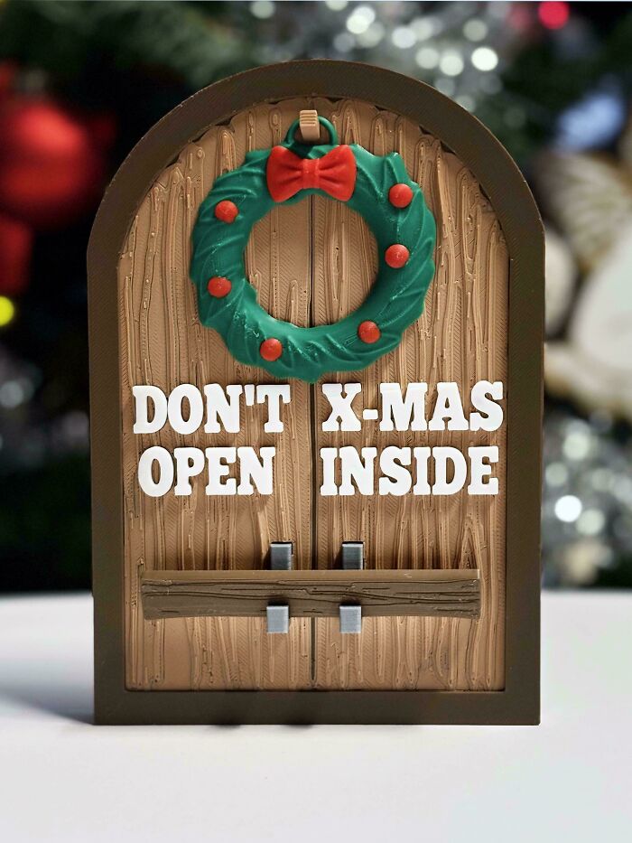 A miniature door decoration with a wreath, featuring a poor sign design that creates a confusing message for X-mas.