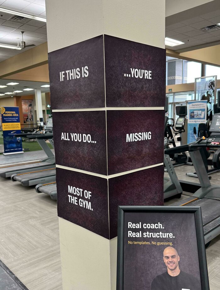 A gym pillar with confusing sign design displaying a message across four panels: IF THIS IS ...YOU'RE ALL YOU DO... MISSING MOST OF THE GYM.