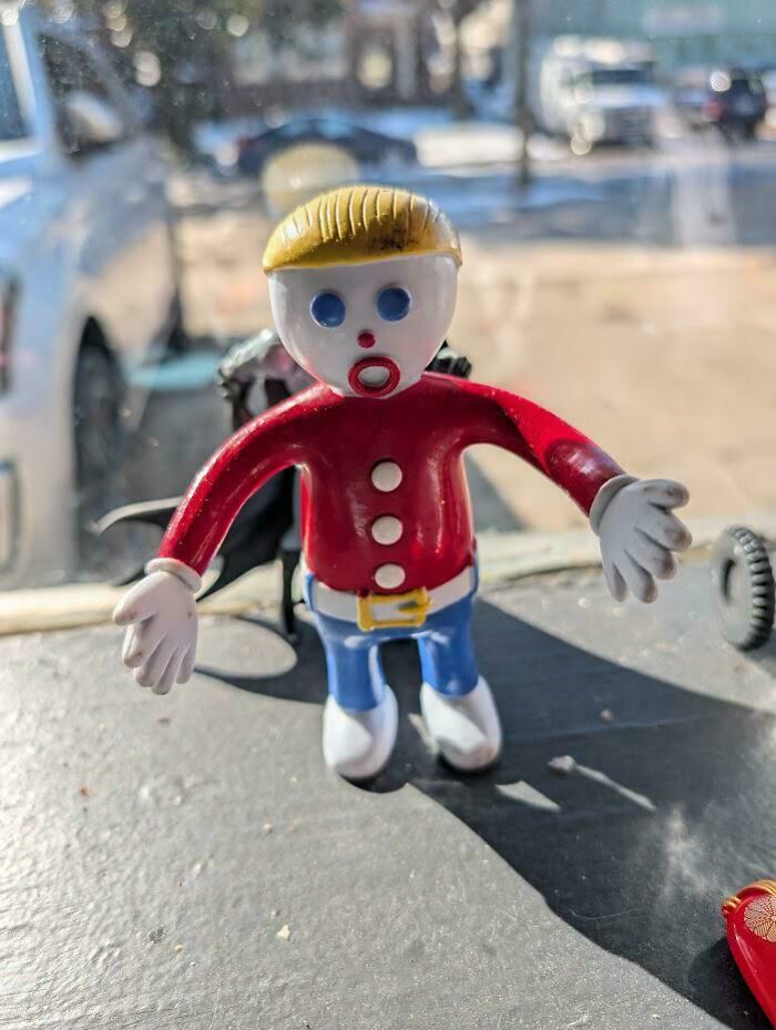 Toy figure with blonde hair and red shirt on a dashboard, evoking nostalgic pics and references from childhood memories.