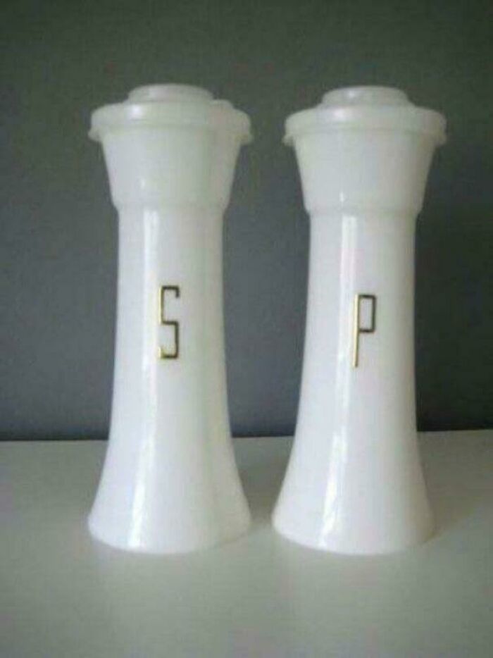 White vintage salt and pepper shakers with gold letters S and P, a nostalgic kitchen item from past decades.
