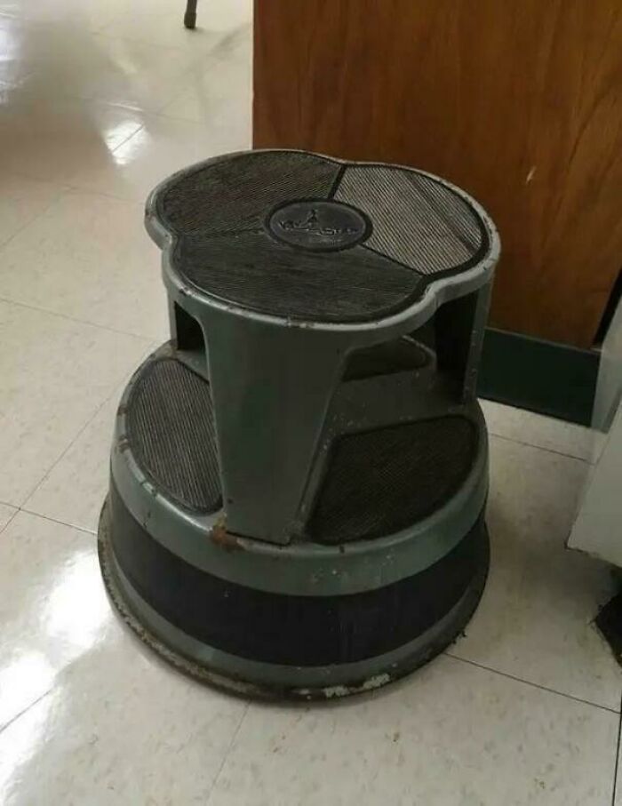 Vintage step stool with rubber grips on tiled floor, a nostalgic item often seen in old libraries or stores.