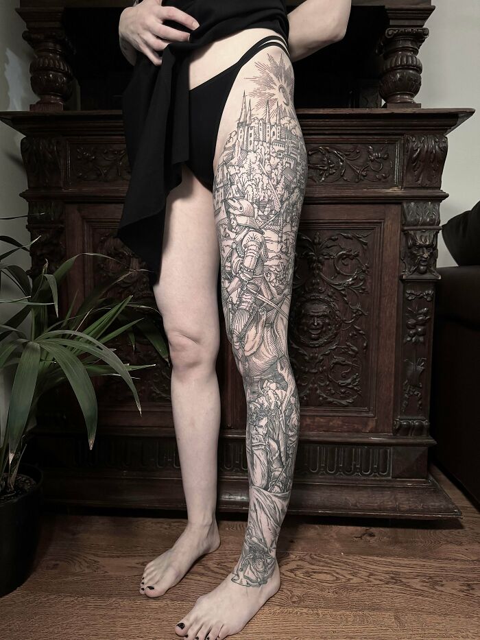 A detailed black and grey leg sleeve tattoo featuring a complex scene, a stunning tattoo that someone is happy to wear forever.