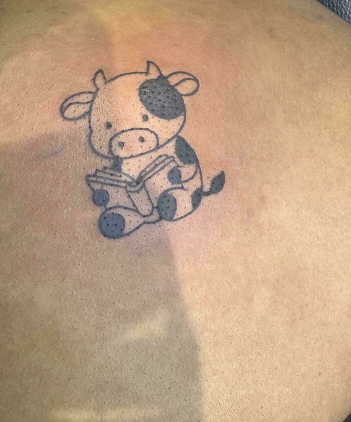 A small, cute calf reading a book, a happy tattoo that people wear forever.