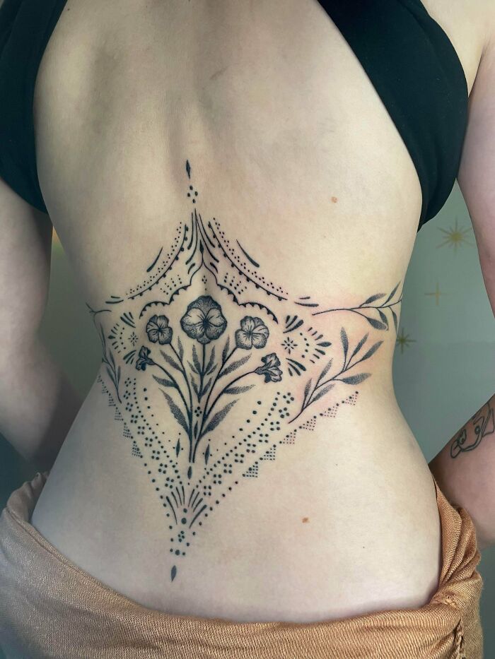 A stunning tattoo of intricate floral and geometric patterns on a person's lower back, emphasizing the beautiful design.