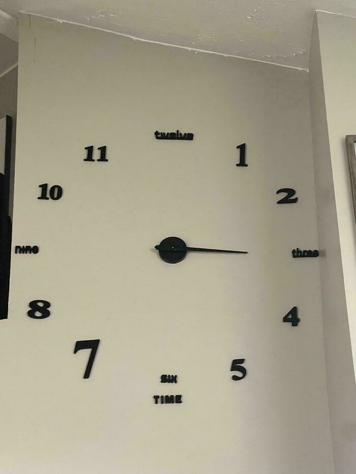 A DIY wall clock with misplaced numbers and words, indicating a failed attempt at installation.