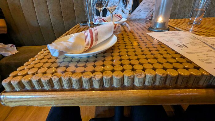 DiWHY table made from corks under glass, with plates, glasses, and a candle, showcasing creative attempts.