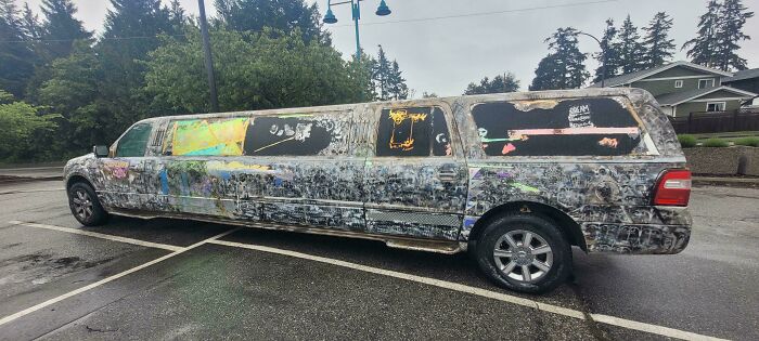 A beat-up, graffiti-covered black limousine parked on a street. A clear example of a DiWHY failure.