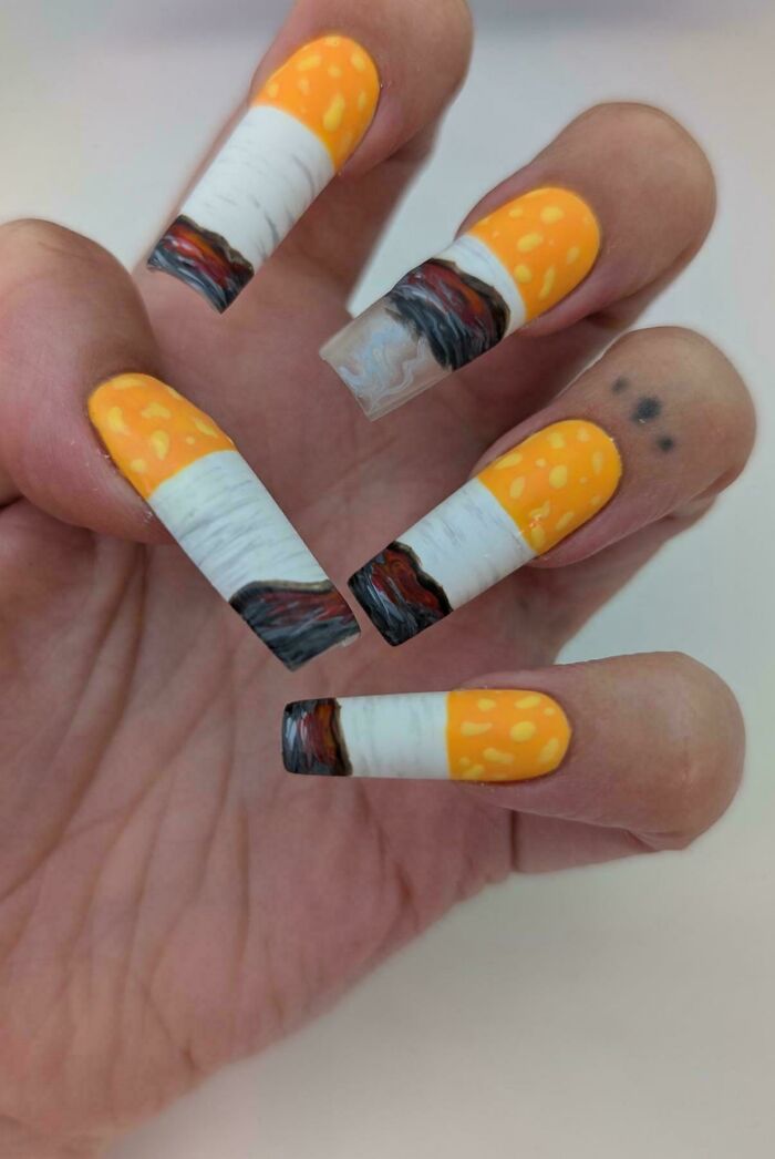 A hand displays DiWHY cigarette-themed acrylic nails, with some burnt ends. A unique, self-made fashion statement.