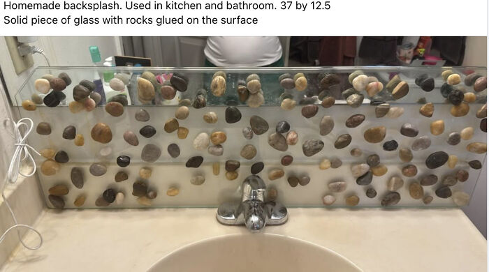 A DiWHY homemade backsplash with rocks glued on glass above a bathroom sink. It seems like a miserable fail.