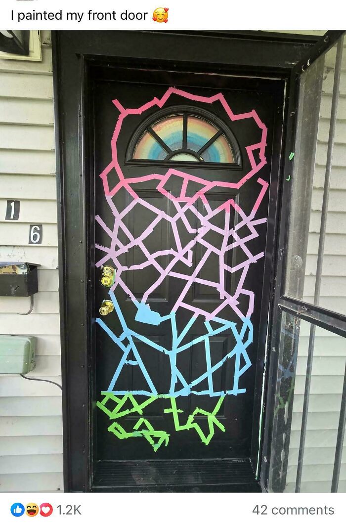 A black front door with a rainbow semicircle window painted with geometric patterns in pink, blue, and green, a DIY project.