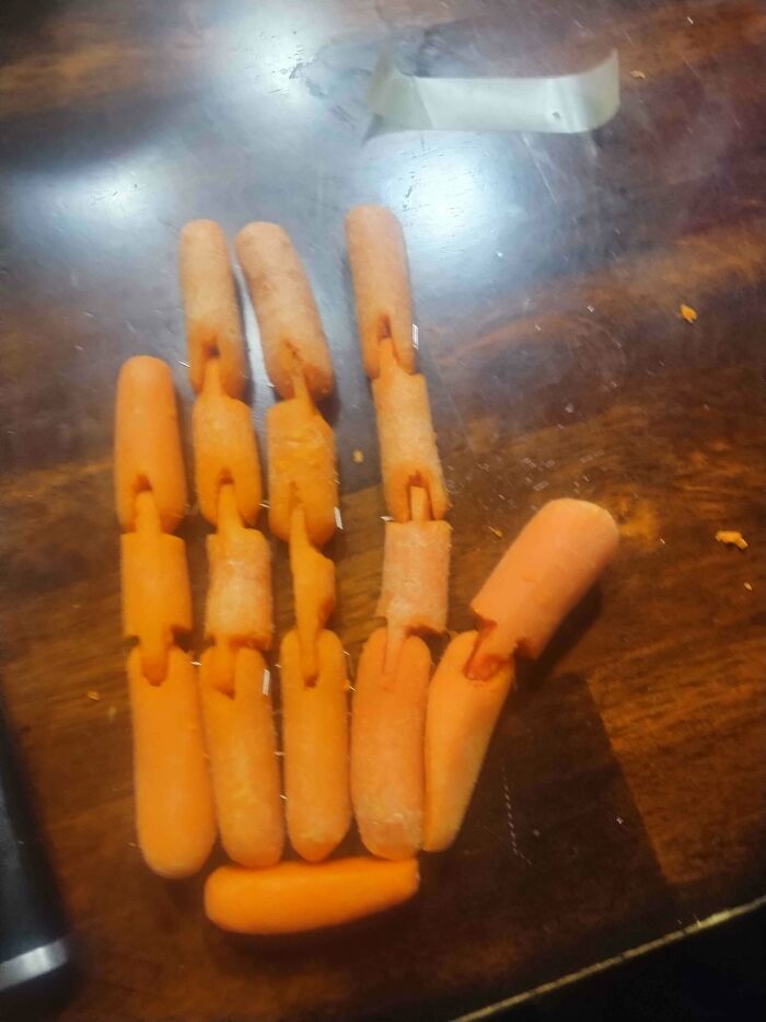A DiWHY attempt: Carrots assembled to resemble a hand on a wooden table, showcasing a DIY project.