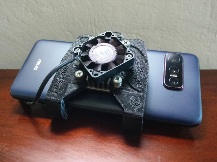 A phone with a "DiWHY" DIY cooling fan attached to its back, highlighting an attempt to do it themselves.