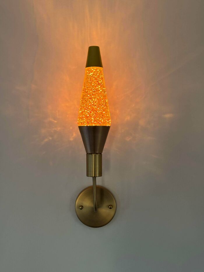 A DiWHY fail? This golden glitter lava lamp sconce glows brightly against a white wall, radiating warmth and light.