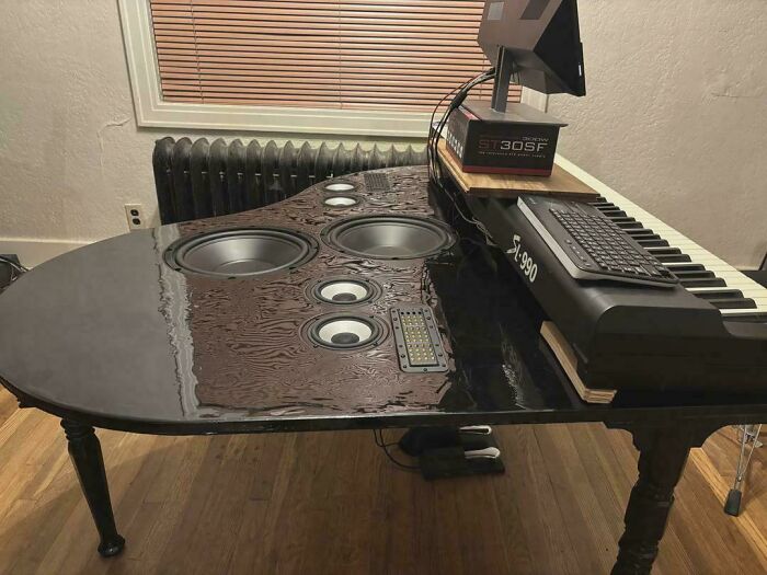A DiWHY project: a piano converted into a speaker table with a keyboard and monitor stand, showcasing DIY attempts.