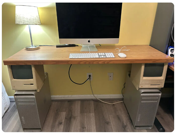 A DiWHY desk made of old Apple computers, supporting a wooden top with a modern iMac.