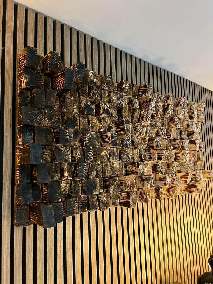 DiWHY wood art from scorched wood blocks on a slatted wall, showcasing a creative DIY project.
