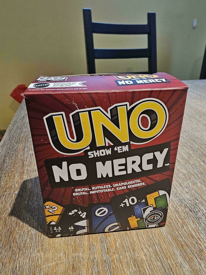 A box for Uno Show 'Em No Mercy board game on a wooden table. Perfect for dads to play together.
